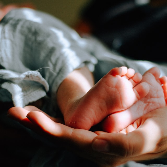 A parent holding a baby's tiny hand